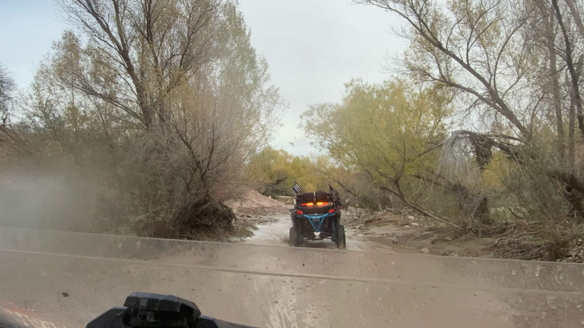 ATV crossing shallow creek through wooded trail