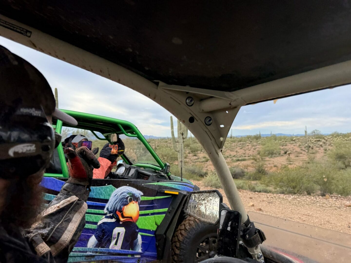 Off-road UTV riders waving in desert