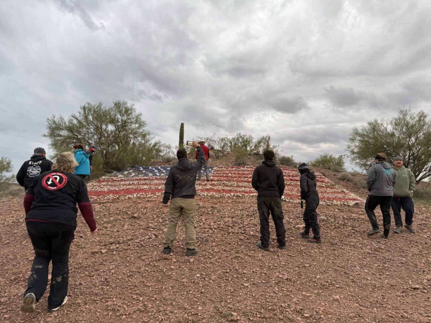 People viewing large American flag painted on hillside