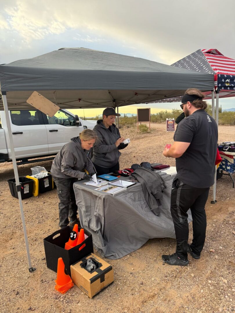 Three people at outdoor canopy information table
