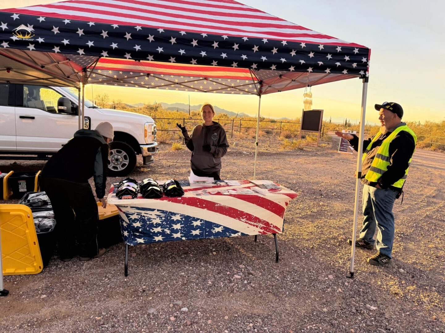 People setting up table under American-flag canopy