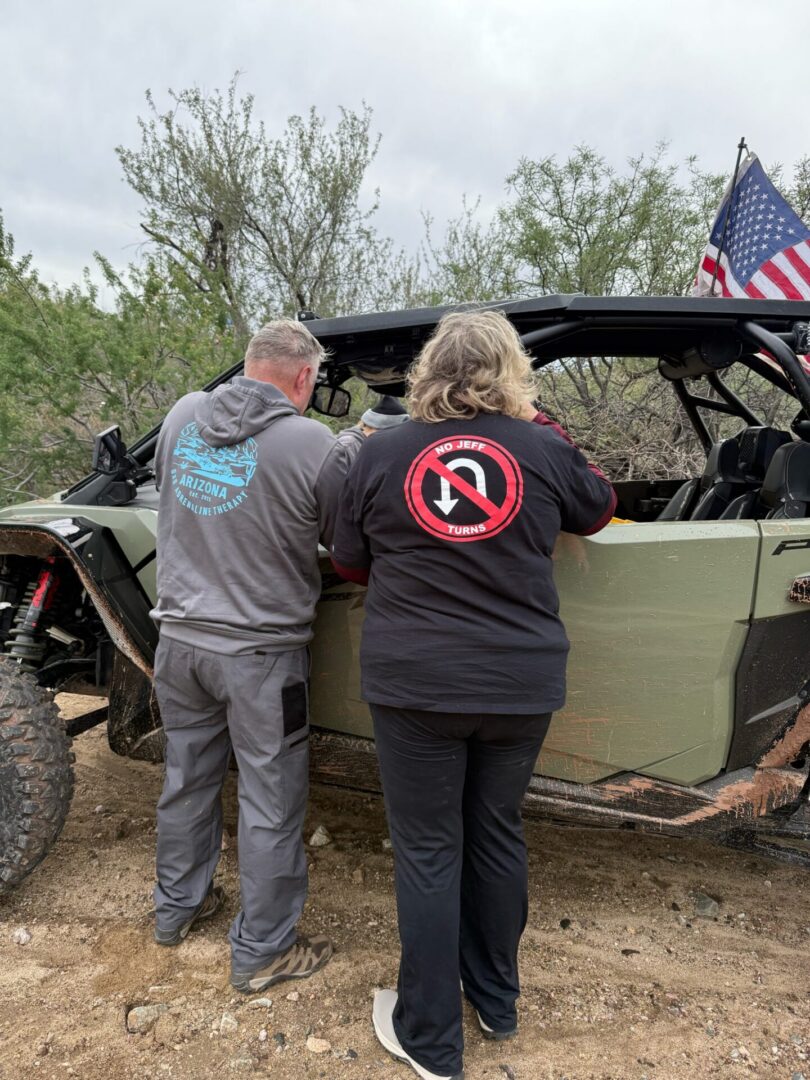 Two people beside off-road UTV with American flag