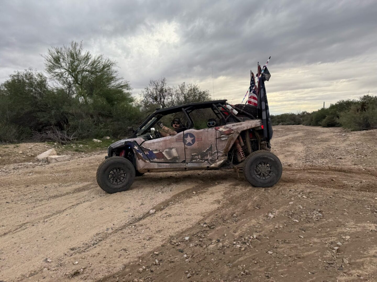 Camouflaged off-road UTV with flags in desert
