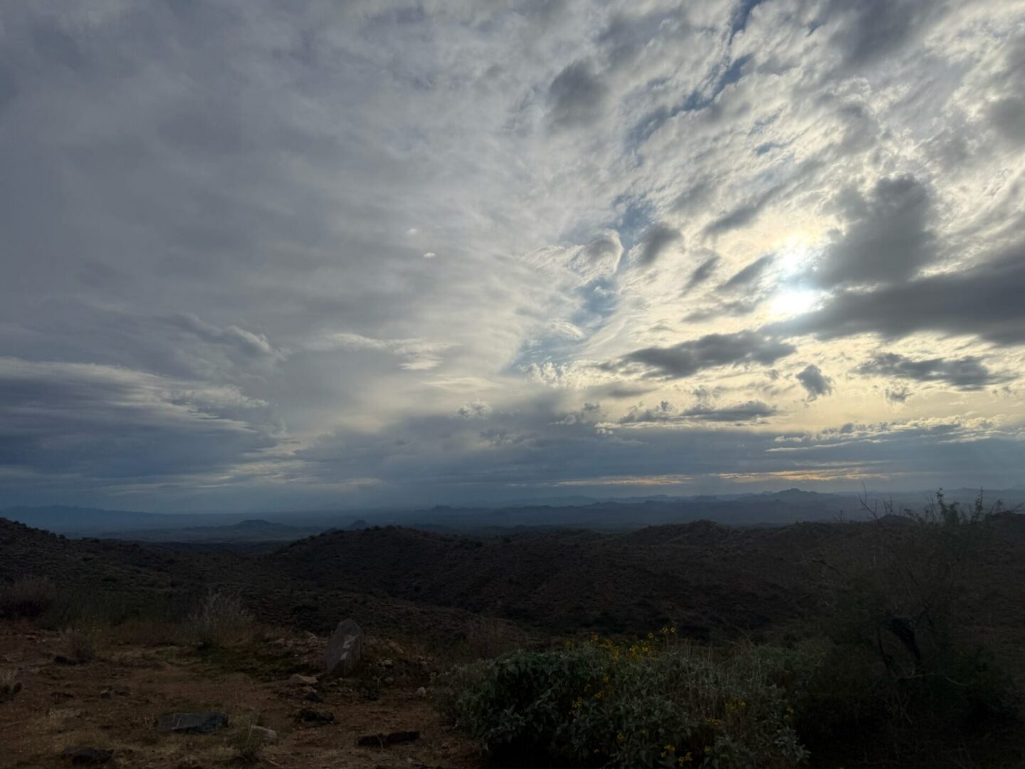 Sun breaking through clouds over desert hills