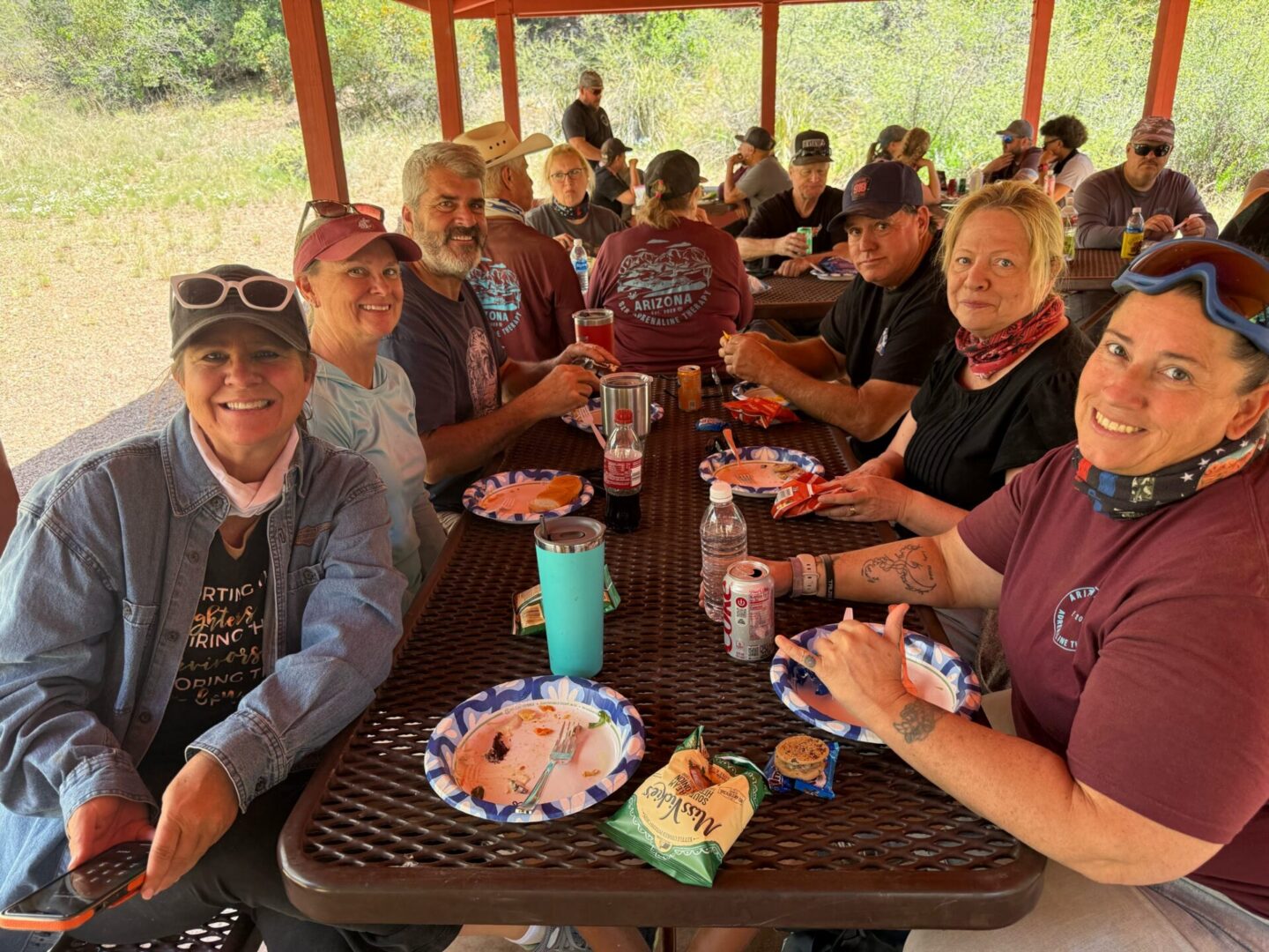 Smiling group eating under picnic pavilion