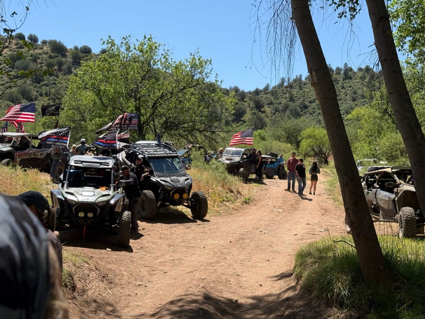 Off-road UTVs with American flags on dirt trail