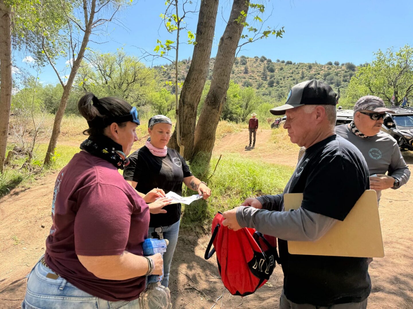 People exchanging supplies outdoors by trees