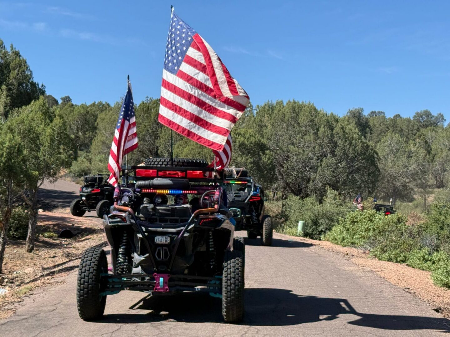 UTVs with American flags on dirt trail