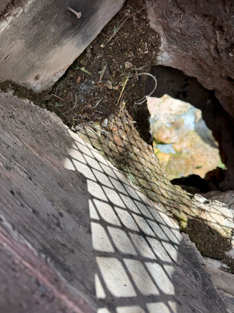 Sunlit hole in wooden deck with mesh shadow