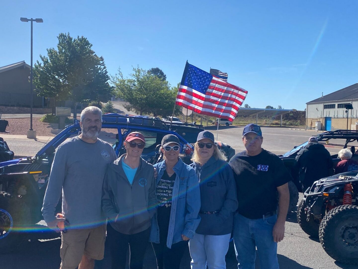 Five people near off-road vehicles with American flag
