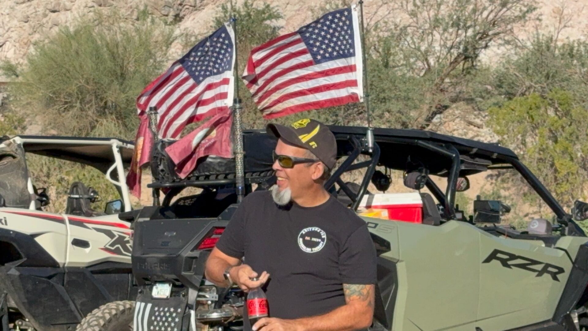 Man in UTV holding soda with American flags