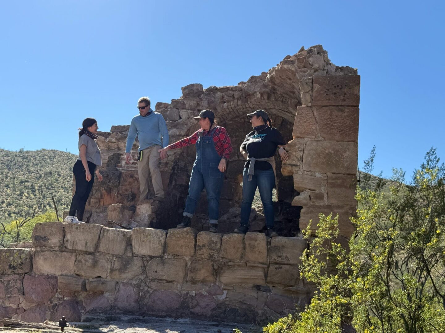 Four people exploring stone ruins in desert