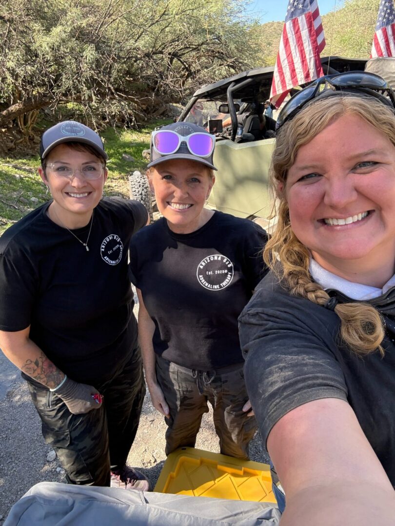 Three smiling women by off-road vehicle and flags