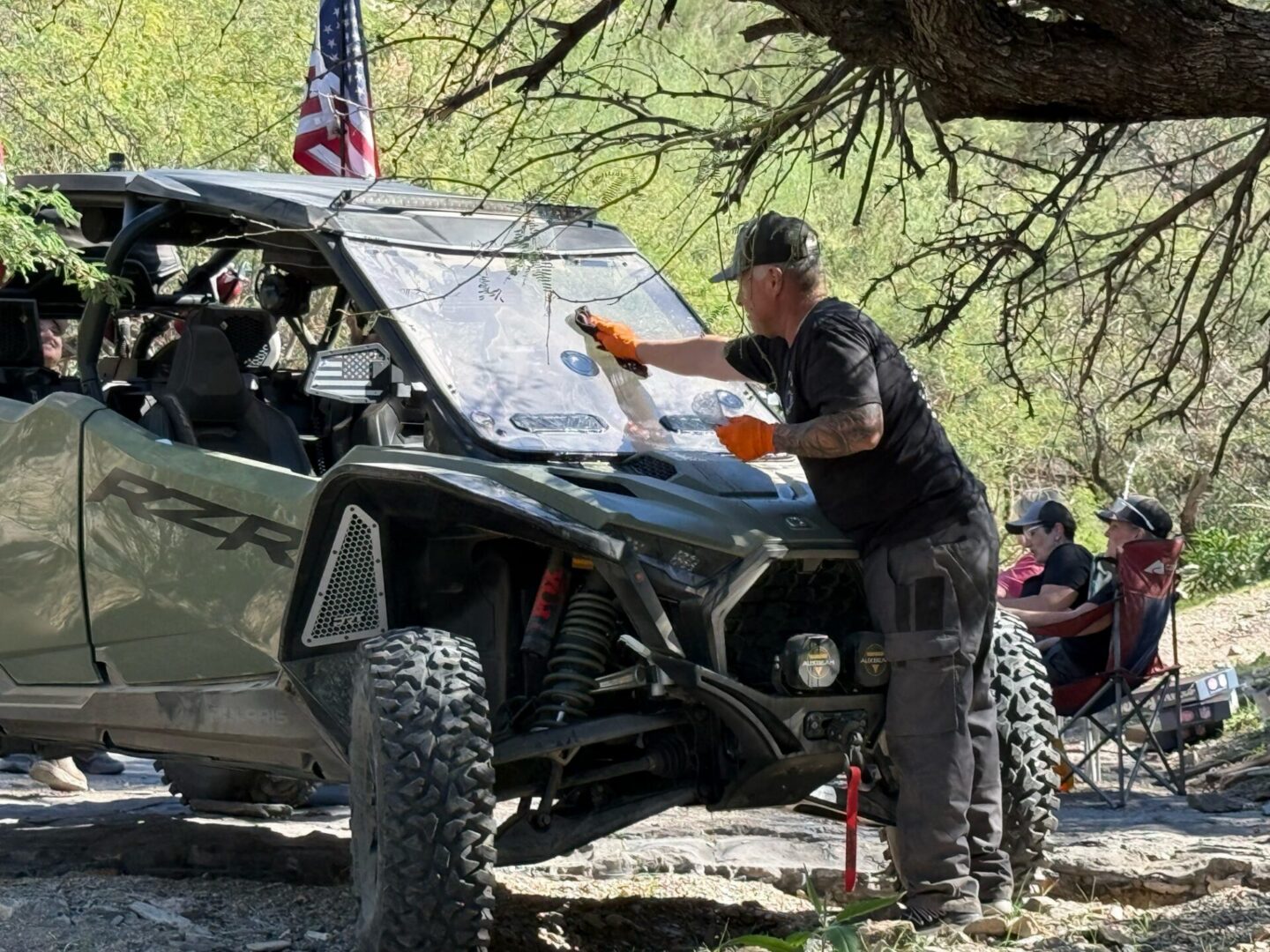 Man cleaning UTV windshield outdoors