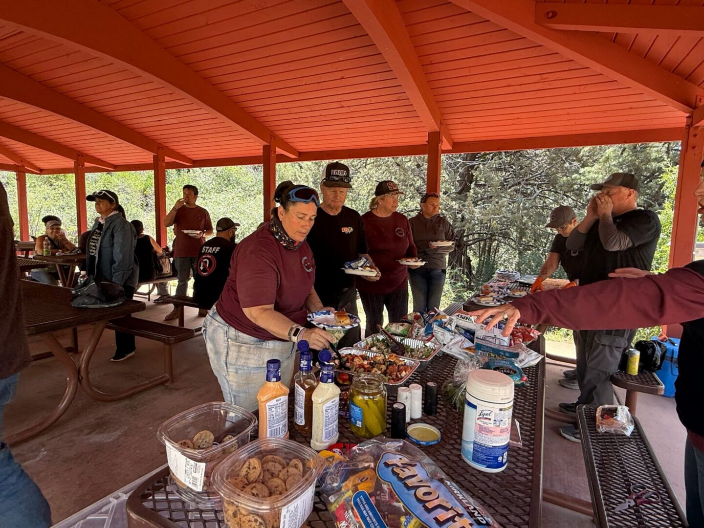 People serving food at outdoor picnic shelter