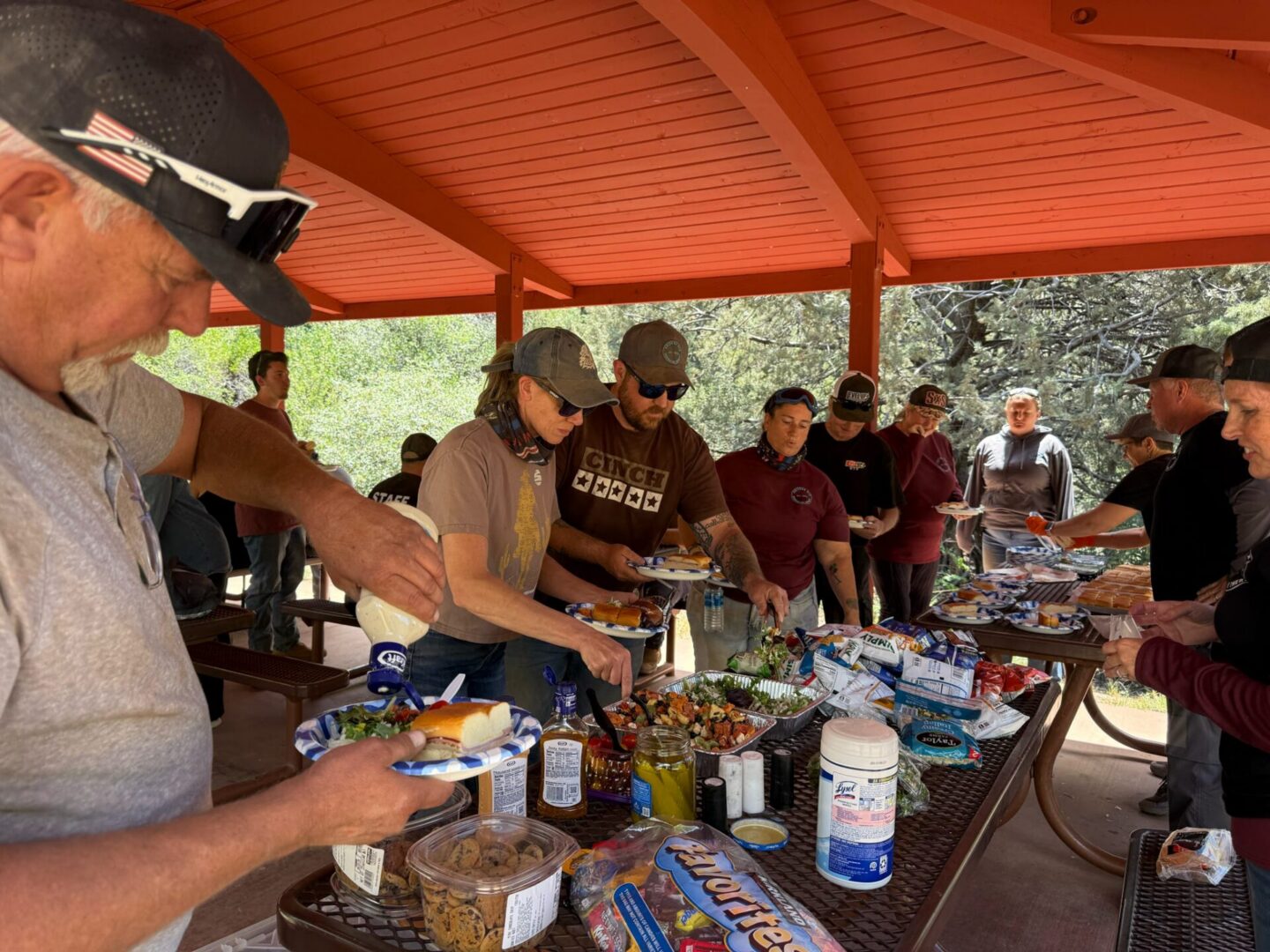 Group serving buffet food under outdoor pavilion