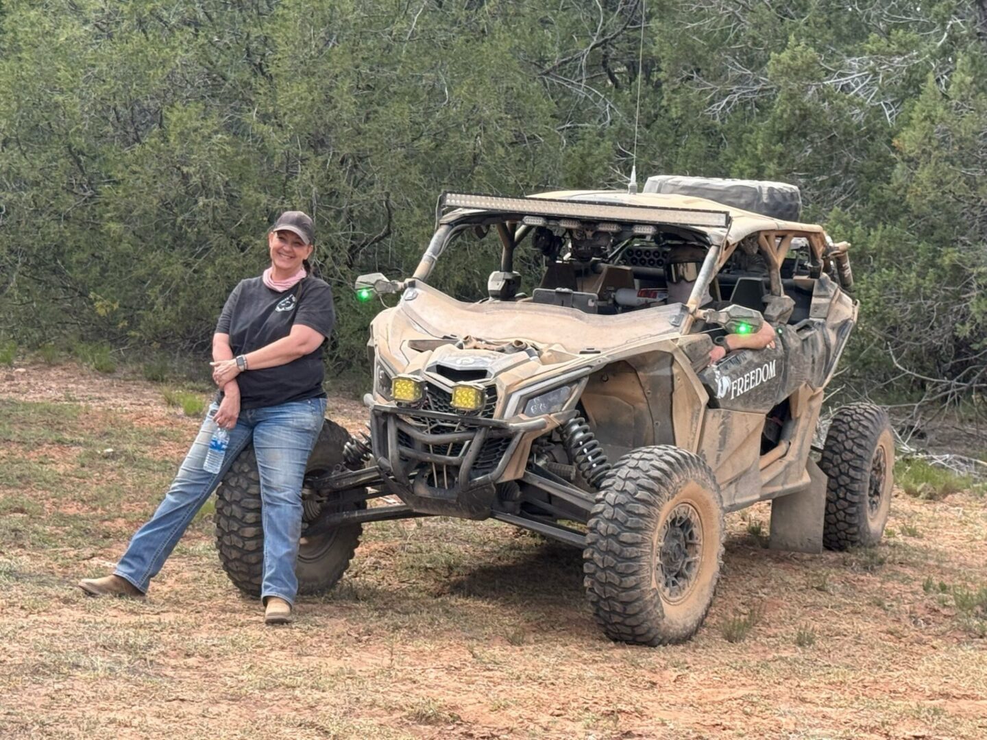 Person leaning against muddy off-road UTV