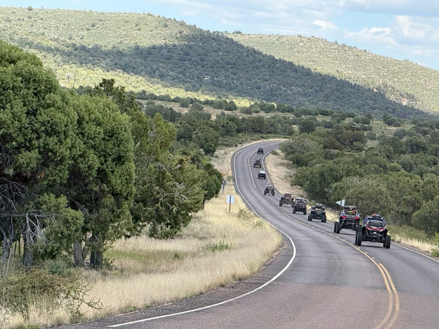Convoy of off-road vehicles on winding country road